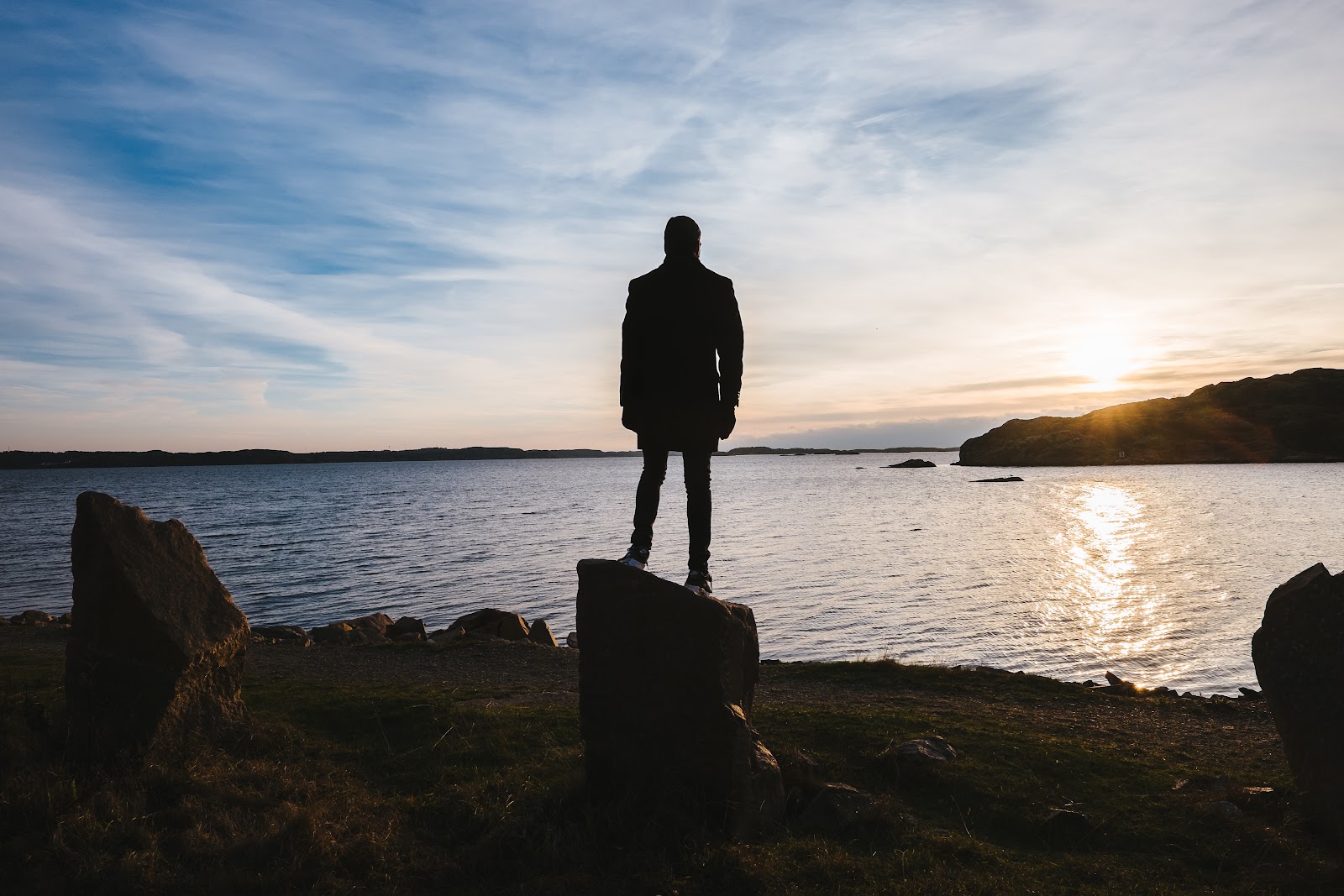 Une personne de dos regardant la vaste expanse de la mer et le coucher du soleil se demandant si ses choix de consommation peuvent avoir un vrai impact sur l'environnement.