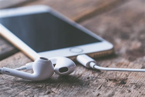 Un iPhone et des écouteurs filaires sur une table en bois