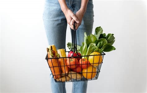 Une personne tenant un panier de fruits et légumes bios frais sans emballage.