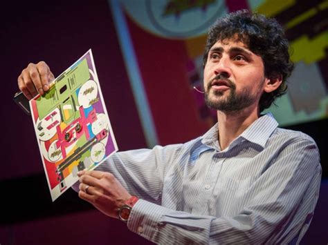 Le fondateur du Foldscope lors d'un discours, tenant un microscope low-tech qui consiste en une feuille de papier multicolore.