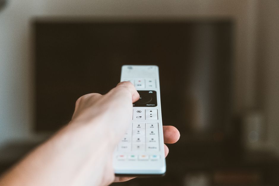 Télécommande devant une télévision, pour illustrer les réglages TNT d’une TV High One